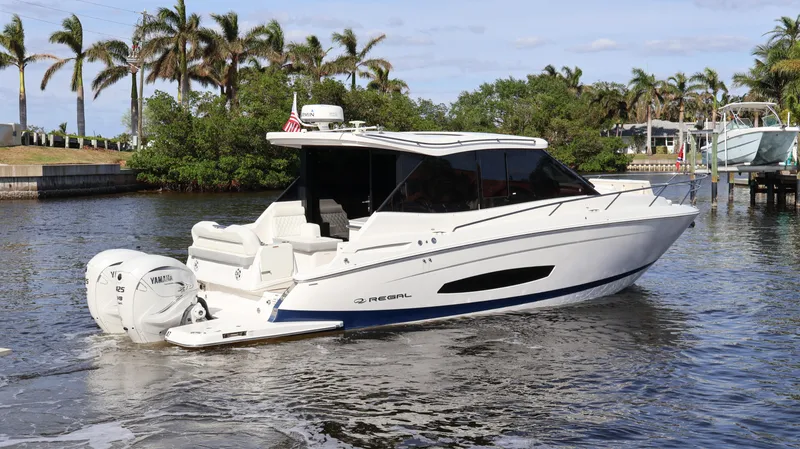 Slide: The Image of 2023 Regal 36 XO boat cruising on a scenic waterway with palm trees. - 6