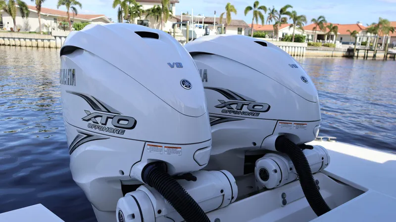 Slide: The Image of Twin Yamaha XTO Offshore engines on a 2023 Regal 36 XO boat, docked by waterfront homes. - 8