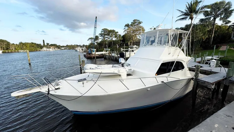 Slide: The Image of 1989 Post 43 Convertible yacht docked by a scenic waterfront with palm trees. - 1