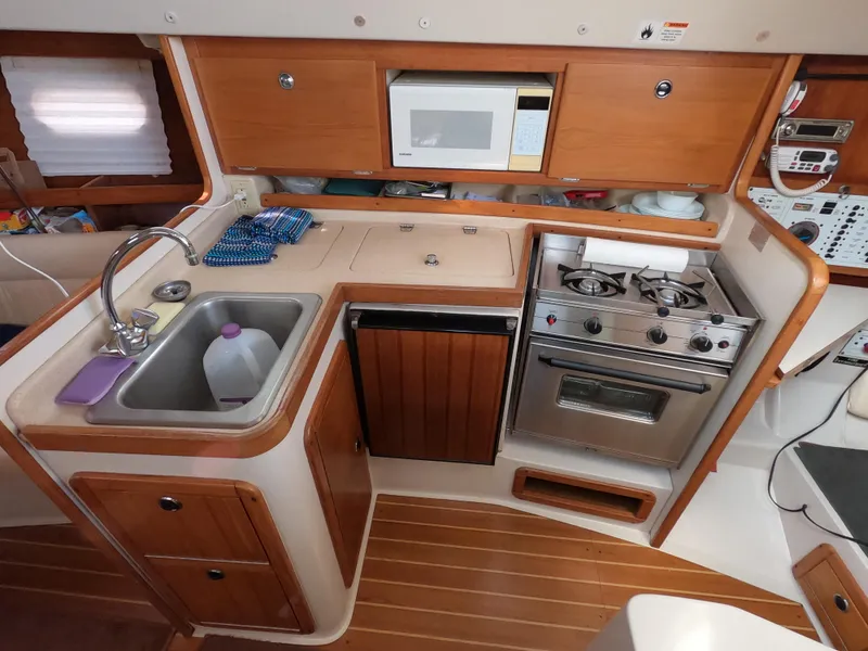 Slide: The Image of Compact kitchen in a 2002 Catalina 310 sailboat with sink, stove, and microwave. - 14