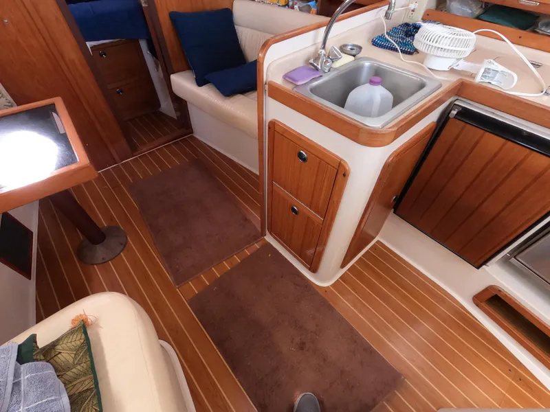 Slide: The Image of Interior of a 2002 Catalina 310 sailboat with wood flooring and compact kitchen area. - 15