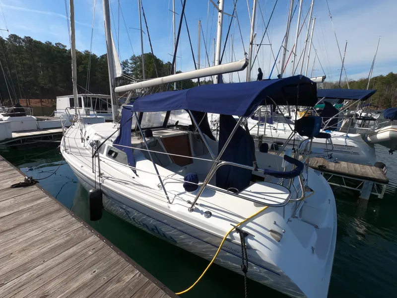 Slide: The Image of 2002 Catalina 310 sailboat docked with blue canopy and white hull. - 2