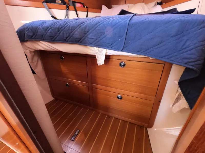 Slide: The Image of Cozy cabin interior of 2002 Catalina 310 sailboat with wooden drawers and blue bedding. - 22