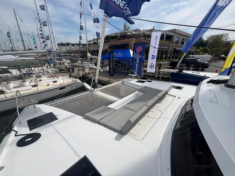 Slide: The Image of 2025 Fountaine Pajot Astrea 42 catamaran with sunbathing area at a marina. - 17