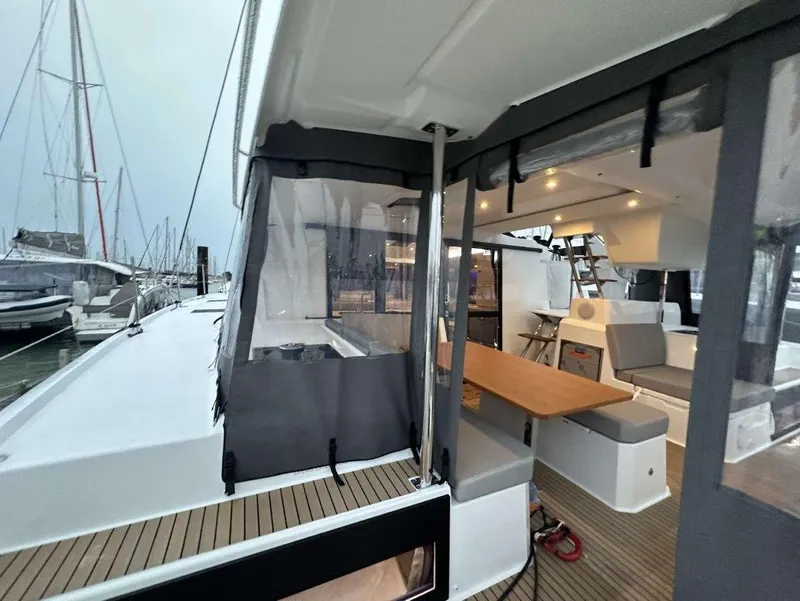 Slide: The Image of 2025 Fountaine Pajot Astrea 42 catamaran interior with seating and table, docked at marina. - 23