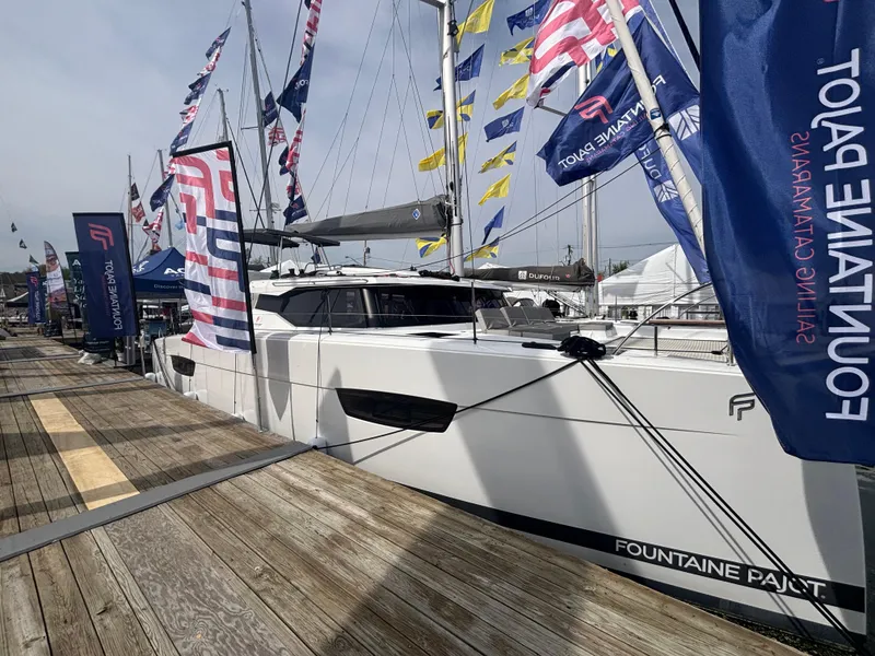 Slide: The Image of 2025 Fountaine Pajot Astrea 42 catamaran docked, surrounded by colorful flags. - 6
