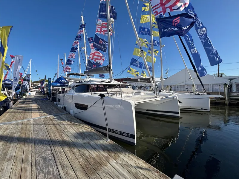 The Image of 2025 Fountaine Pajot Astrea 42 catamaran docked, adorned with colorful flags under clear blue sky. - 0