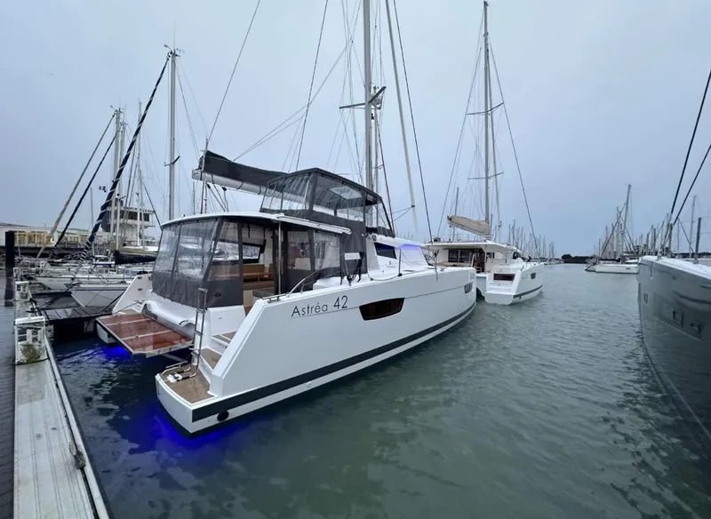 Slide: The Image of 2025 Fountaine Pajot Astrea 42 catamaran docked in marina, featuring sleek design and blue underwater lights. - 20