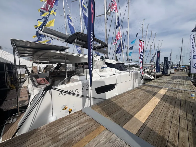Slide: The Image of 2025 Fountaine Pajot Astrea 42 catamaran docked at marina with colorful flags. - 3