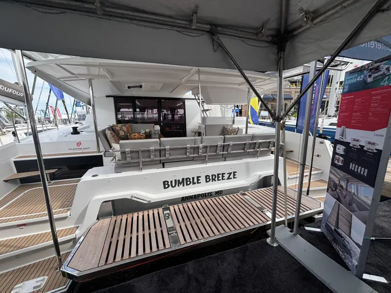Slide: The Image of 2025 Fountaine Pajot Astrea 42 catamaran, "Bumble Breeze," docked with elegant seating and wooden deck. - 31