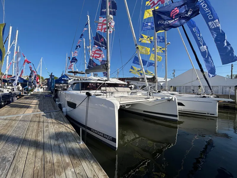 Slide: The Image of 2025 Fountaine Pajot Astrea 42 catamaran docked at marina with colorful flags. - 5