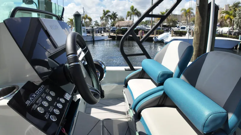 Slide: The Image of 2022 Saxdor SX200 boat interior with steering wheel and seating, docked at marina. - 13
