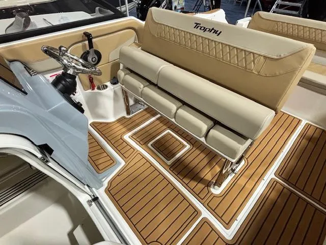 Slide: The Image of 2025 Bayliner T22 SC boat interior with tan seating and wood-patterned flooring. - 13