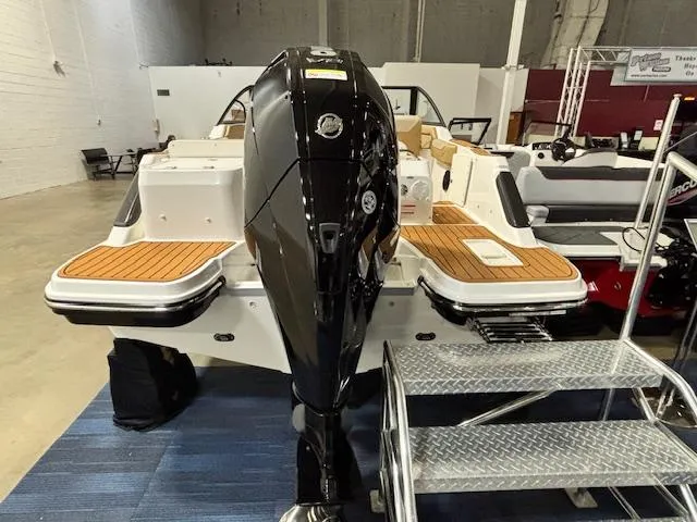 Slide: The Image of 2025 Bayliner T22 SC boat with powerful outboard motor, displayed indoors on blue carpet. - 6