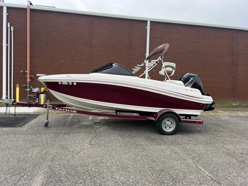 Slide: The Image of 2016 Tahoe 450 TF boat on trailer, parked outdoors against a brick wall. - 1
