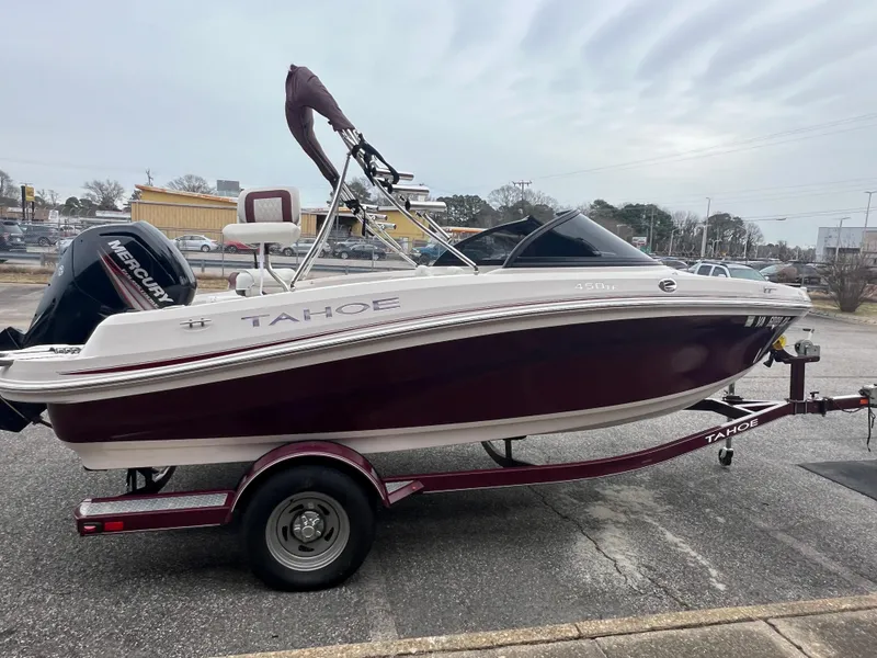 Slide: The Image of 2016 Tahoe 450 TF boat on trailer, maroon and white, parked outdoors. - 8