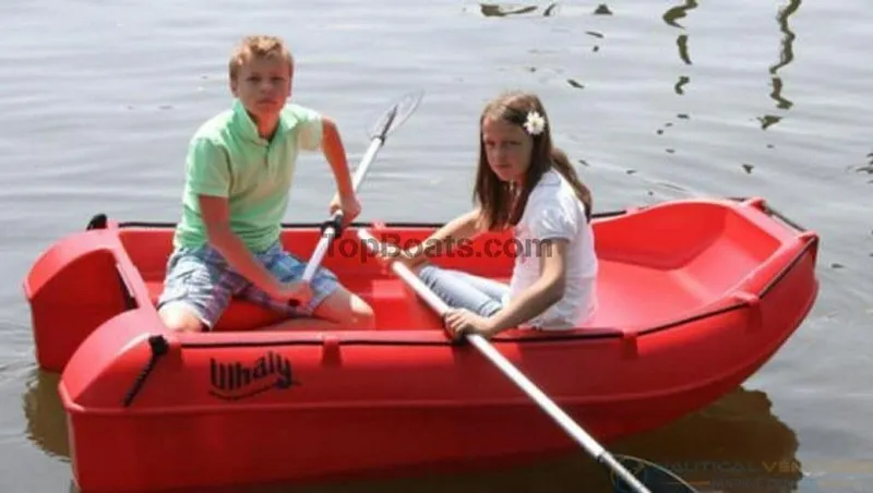 Slide: The Image of Two children rowing a red 2022 Whaly 210 boat on calm water. - 4