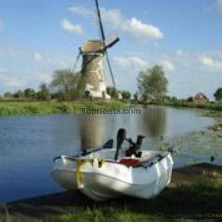 Slide: The Image of 2022 Whaly 210 boat by a river with a windmill in the background. - 9