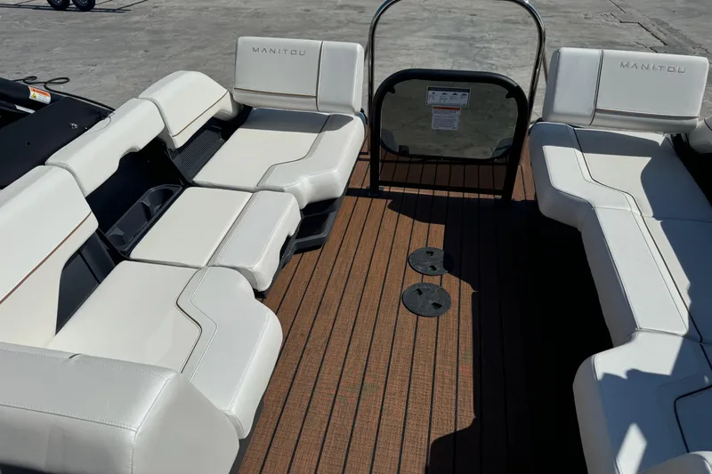 Slide: The Image of 2025 Manitou 26' Explore Navigator boat interior with white seating and wooden deck. - 8