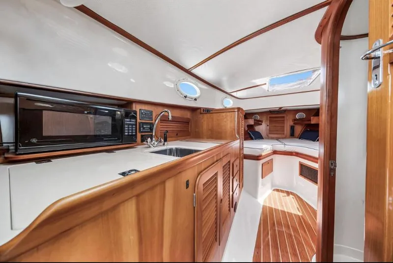 Slide: The Image of Interior of 2002 Hinckley Picnic Boat EP, featuring a cozy cabin with wood finishes. - 15