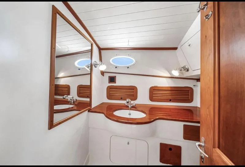 Slide: The Image of Elegant 2002 Hinckley Picnic Boat EP bathroom with wooden accents and round porthole window. - 16