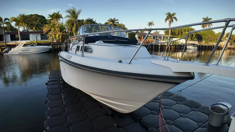 Slide: The Image of 1996 Grady-White Voyager boat docked on calm water with palm trees in the background. - 17