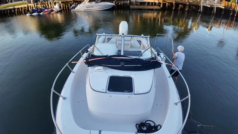 Slide: The Image of 1996 Grady-White Voyager boat docked in calm waters, with a person securing it. - 18