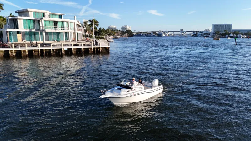 Slide: The Image of 1996 Grady-White Voyager boat cruising near modern waterfront homes. - 5