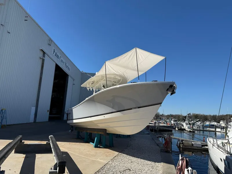 Slide: The Image of 2019 Regulator 31 boat docked near marina with canopy, clear blue sky. - 2