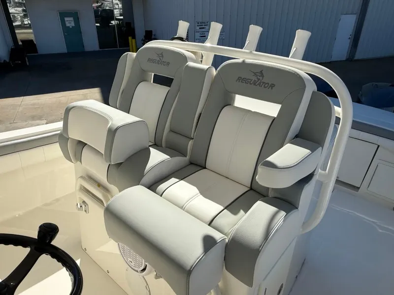 Slide: The Image of 2019 Regulator 31 boat seats with gray and white upholstery in a marina setting. - 42