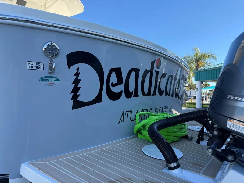 Slide: The Image of 2019 Regulator 31 boat with custom "Deadicated" decal, docked with palm trees in background. - 8