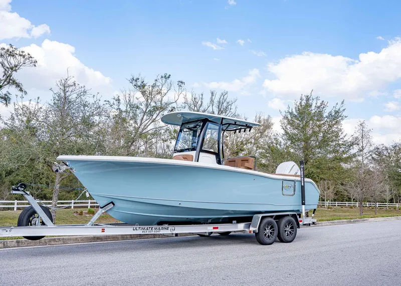 Slide: The Image of 2025 Sea Hunt Ultra 255 SE boat on trailer, parked on a road with trees in background. - 1