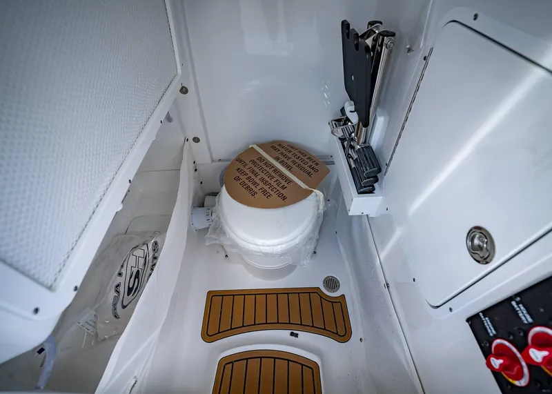 Slide: The Image of Interior of 2025 Sea Hunt Ultra 255 SE boat, featuring a compact marine toilet. - 29