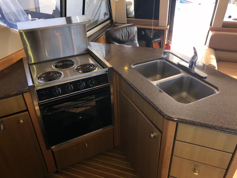 Slide: The Image of 2002 Bayliner 39 Motor Yacht kitchen with stove, double sink, and wooden cabinetry. - 17