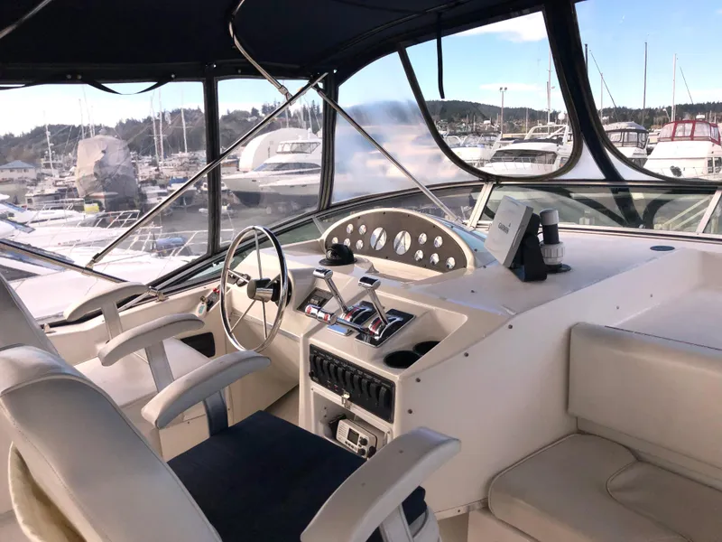 Slide: The Image of 2002 Bayliner 39 Motor Yacht helm with marina view, featuring modern controls and seating. - 5