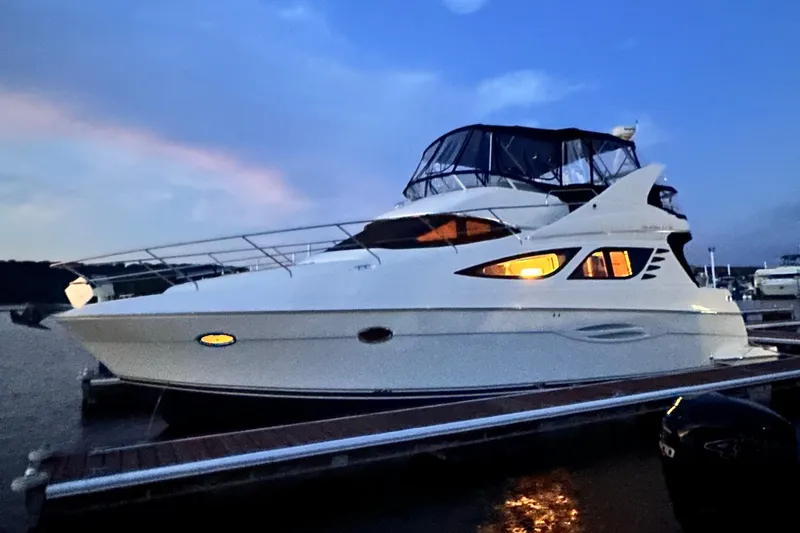 The Image of 2006 Silverton 43 Sport Bridge yacht docked at sunset, illuminated windows. - 0