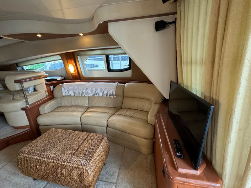 Slide: The Image of Interior of 2006 Silverton 43 Sport Bridge with beige sofa, TV, and wicker table. - 14