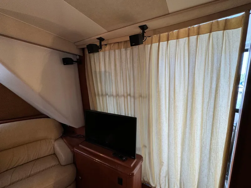 Slide: The Image of Interior of 2006 Silverton 43 Sport Bridge with TV, beige sofa, and curtains. - 15