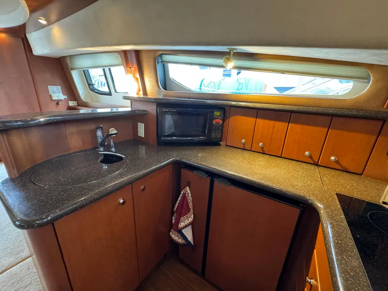 Slide: The Image of 2006 Silverton 43 Sport Bridge yacht kitchen with microwave, sink, and wooden cabinets. - 19