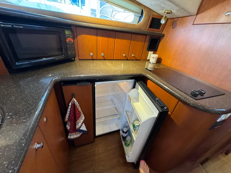 Slide: The Image of 2006 Silverton 43 Sport Bridge kitchen with microwave, fridge, and wooden cabinetry. - 20