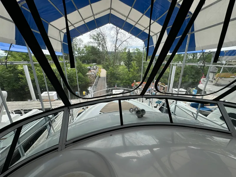 Slide: The Image of 2006 Silverton 43 Sport Bridge yacht under canopy, docked near lush greenery. - 48