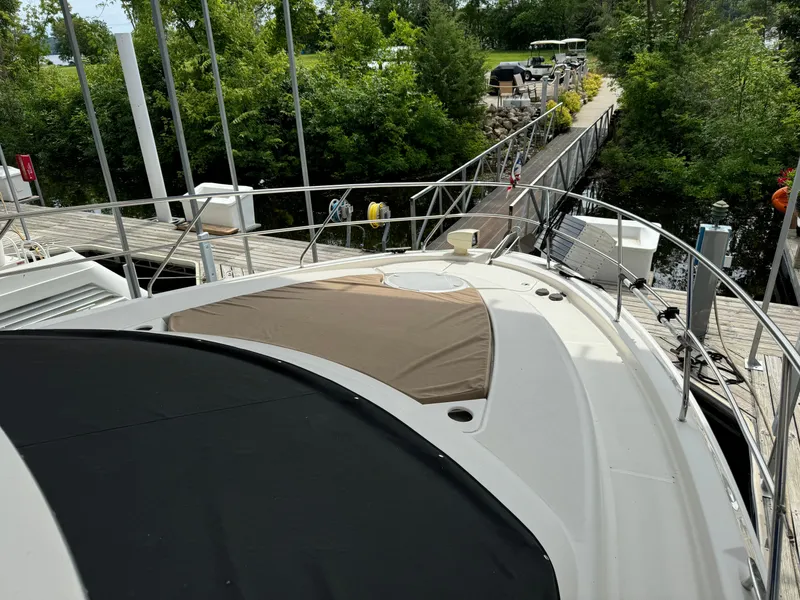 Slide: The Image of 2006 Silverton 43 Sport Bridge yacht docked near lush greenery and a wooden walkway. - 49