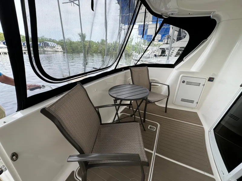 Slide: The Image of 2006 Silverton 43 Sport Bridge yacht deck with chairs and table, overlooking marina. - 9