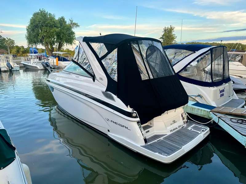 Slide: The Image of 2022 Regal 28 Express boat docked in a marina, featuring a sleek design and black canopy. - 3