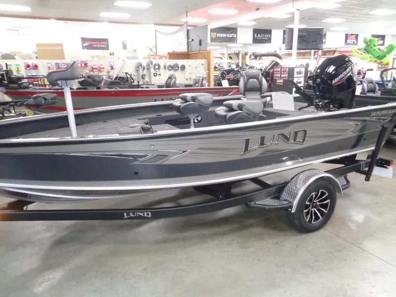 Slide: The Image of 2025 Lund 1875 Pro Guide fishing boat displayed in showroom with modern features. - 0