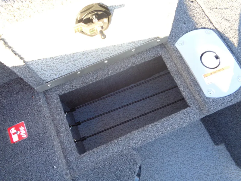 Slide: The Image of 2025 Lund 1875 Pro Guide boat interior with rod storage compartment and carpeted flooring. - 18