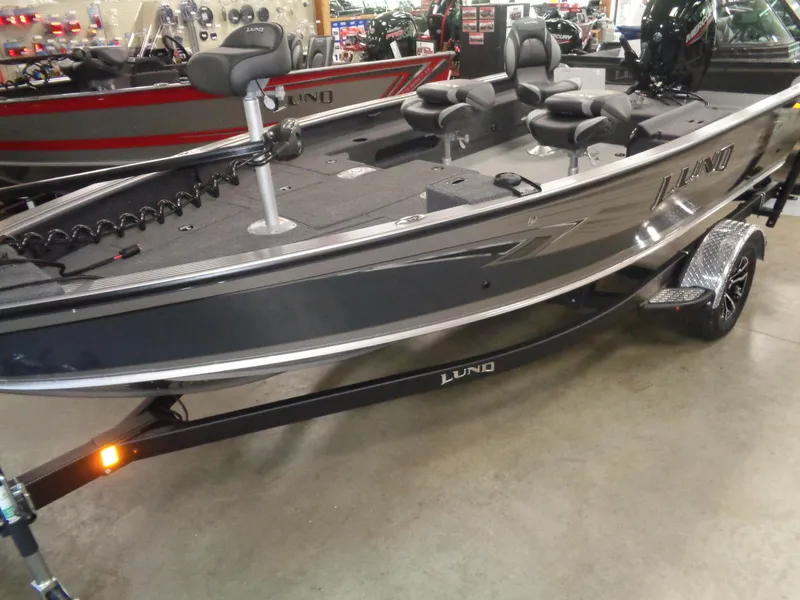 Slide: The Image of 2025 Lund 1875 Pro Guide fishing boat in showroom, featuring sleek design and comfortable seating. - 26