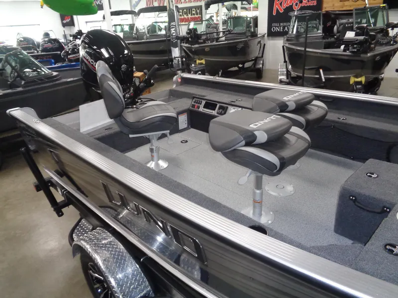 Slide: The Image of 2025 Lund 1875 Pro Guide fishing boat interior with seating and motor in showroom. - 29