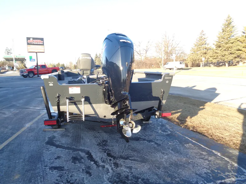 Slide: The Image of 2025 Lund 1875 Pro Guide boat, rear view, parked on pavement, sunny day. - 8