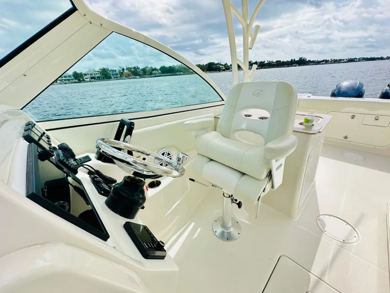 Slide: The Image of 2014 Sailfish 275 DC boat interior with captain's chair and steering wheel, overlooking water. - 4